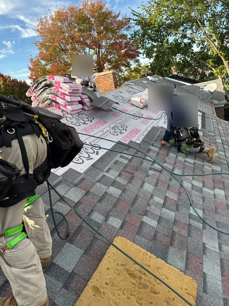 Roofing crew laying new architectural shingles over pink-and-white synthetic underlayment, with shingle bundles stacked near the chimney